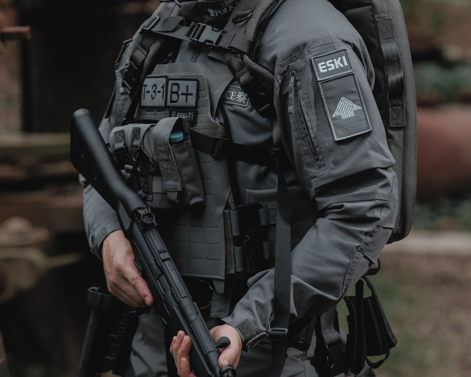 Law enforcement officer wearing Eski tactical vest and carrier with shotgun in industrial setting