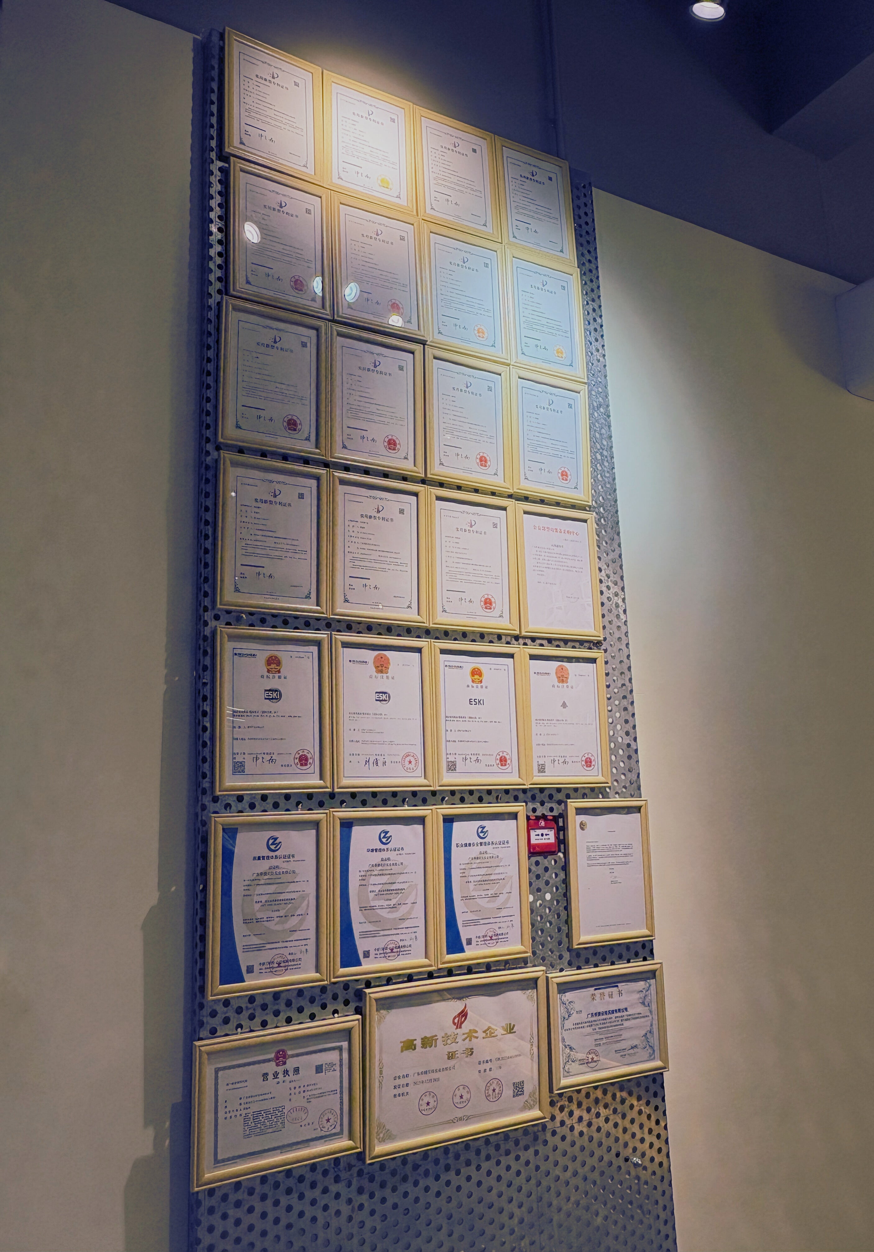 Wall displaying multiple framed certificates on a blue and white checkered pattern